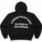 A black pullover hoodie shown from the back, featuring the phrase 'CONGRATULATIONS YOU WOKE UP THIS MORNING' printed in white arched text across the back.